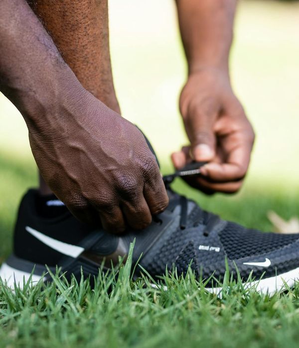 Person tying shoelaces on sports shoes, symbolizing the first step to practice.